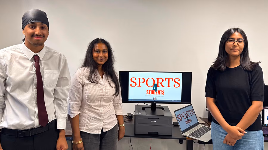 A team beside the screen showing the sports app they built.