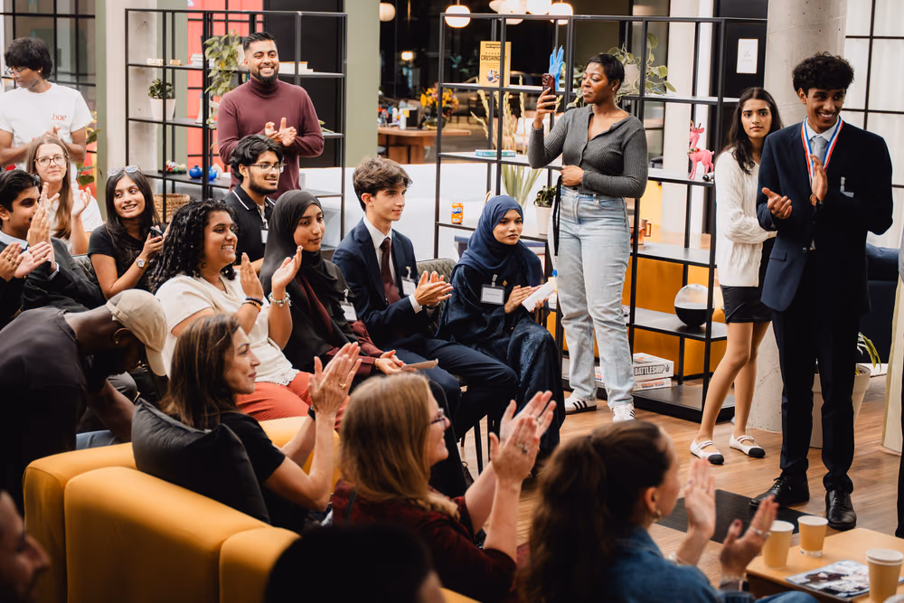 Students and guests clapping from the sofas and the floor.
