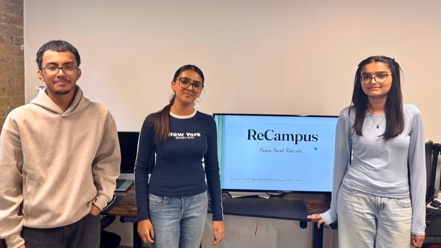 A team beside the screen showing the resale product they built.